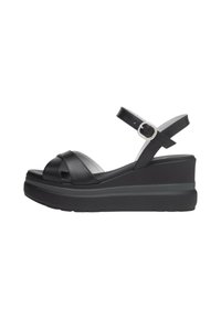 Sandali wedge neri in pelle con design a fascia incrociata, cinturino alla caviglia regolabile e suola piattaforma testurizzata. Presenta un accentuato con fibbia argentata.