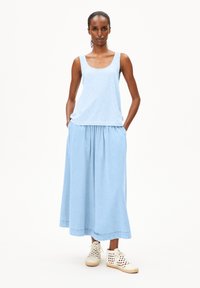 Light blue striped tank top with wide straps paired with a flowy light blue ankle-length skirt and white perforated ankle shoes.
