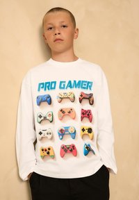 Weißes Langarm-T-Shirt mit einer bunten Grafik verschiedener Gaming-Controller und dem Text "PRO GAMER" in Blau. Angenehmer Stoff, lockere Passform.
