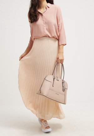 Blusa rosa chiaro con chiusura a bottoni frontale, gonna plissettata crema, borsa rosa chiaro con dettagli in argento e sneakers chiare.