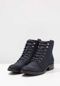 Stivaletti alla caviglia blu navy in tessuto texturizzato, con lacci, occhielli metallici e tacco a blocco basso. Design semplice, costruzione resistente.