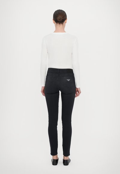 Svarta slim-fit jeans med fem fickor, midja med medelhög höjd och en subtil logotypdetalj på bakfickan. Slät denimtextur.