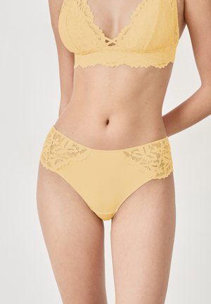 Geel kanten bralette en bijpassende slip, met ingewikkelde kantdetails, golvende randen en een gladde stoftextuur.