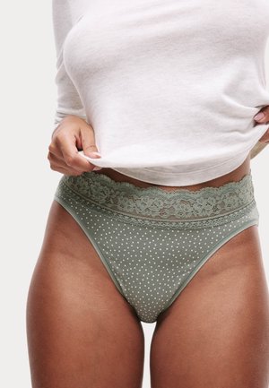 Groene bikini slip met stippen en een kanten tailleband, voorzien van fijne bloemenaccenten. Glad textuur, middelhoge pasvorm.