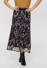 Jupe midi florale en tissu léger et semi-transparent bleu marine, ornée d'un mélange de fleurs blanches, roses et brunes ; dotée d'une taille noire.