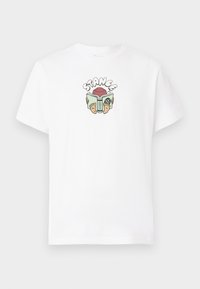 White cotton t-shirt featuring a colorful graphic print with the word "STANCE" above a character holding a book and wearing sandals.