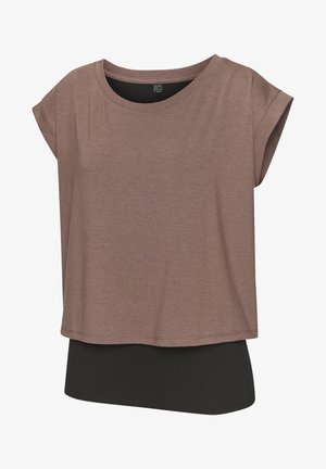 Braunes Kurzarmoberteil mit lockerem Schnitt, getragen über einem schwarzen Unterteil. Hergestellt aus einem glatten, weichen Stoff mit dezenter Textur.