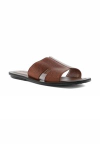 Brown leather slide sandal featuring textured upper, open design, and contrasting black rubber sole. No heel, slip-on style suitable for casual wear.
