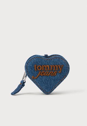 Heart-shaped blue denim pouch with orange embroidered "tommy jeans" logo, featuring a zipper and decorative stitching details.