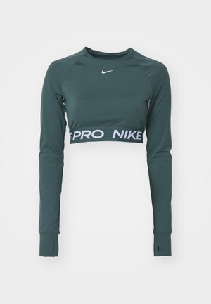 Mørkegrønn langermet crop topp laget av glatt stoff. Har et logo og et kontrastfylt hvitt bånd med "PRO NIKE" tekst ved kanten.