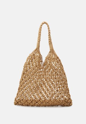 Beige macramé-stijl netzak met gevlochten handvatten, opengeweven patroon en een driehoekige vorm tegen een effen lichte achtergrond.