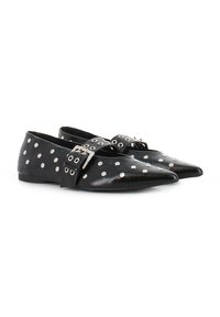 Bailarinas de cuero negro con punteras puntiagudas, adornadas con tachuelas circulares plateadas y una cinta ancha con hebilla que cruza el empeine.