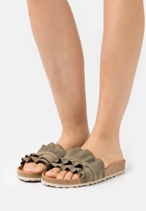 Sandalias de ante verde con un diseño con volantes, suela de corcho ligera y un acabado texturizado. Tienen la punta descubierta y un estilo plano y casual.