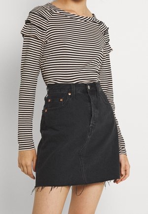 Pruhované tričko s dlouhým rukávem v béžové a černé barvě, kombinované s černou denimovou minisukní s neopracovaným lemem a předními kapsami.