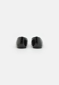 Svarta loafers i glansigt läder med krokodilprägling, med låg profil och rund tå, liten klack och bakre flik.