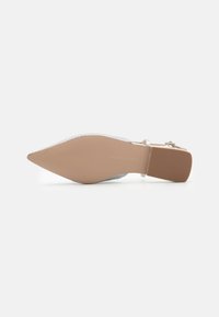 Pointed-toe high heel shoe with a transparent strap, silver embellishments, beige sole, and textured rubber on the heel for grip.