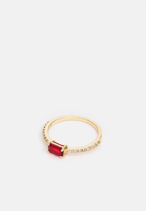 Bague fine en or avec une pierre précieuse rouge rectangulaire au centre et de petites pierres claires incrustées sur la moitié de l'anneau.