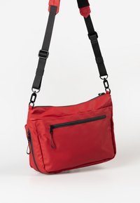 Borsa a tracolla rossa in nylon con cinturino nero regolabile. Presenta una tasca frontale con zip e un vano principale con chiusura a zip.