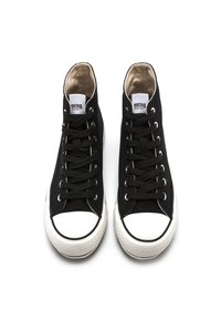 Sneaker alte nere con tomaia in tessuto, punta in gomma bianca e lacci neri. Presentano un'etichetta con logo sulla linguetta e suola testurizzata.