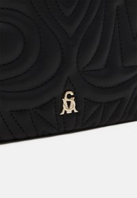 Bolso de mano de cuero negro con diseño de patrón en relieve, herrajes de logo en tono dorado y costuras en contraste.