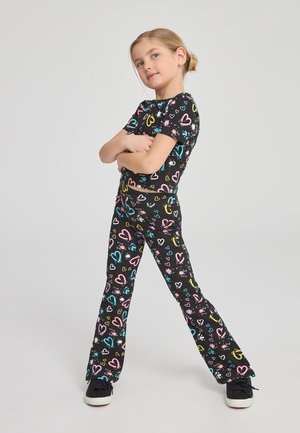 Completo nero a due pezzi con maniche corte e pantaloni svasati, decorato con cuori colorati e motivi a spruzzo. Il materiale sembra elastico.
