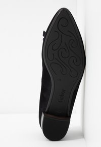 Semelle de chaussure noire à bout pointu avec un motif de rainures en spirale, taille 4½, et le nom de la marque Gabor embossé près du talon.