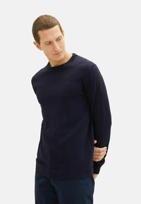 Marineblauwe crewneck sweater van zachte brei. Kenmerkt zich door een geribde halslijn en manchetten met een subtiel logo-opdruk op de borst.