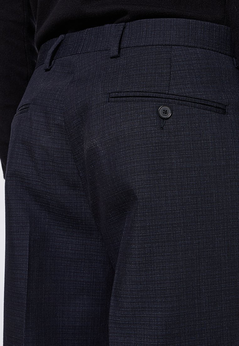 Pantalones de un azul marino texturizado con un bolsillo trasero abotonado y lazos para cinturón, presentando un patrón sutil y un ajuste a medida.