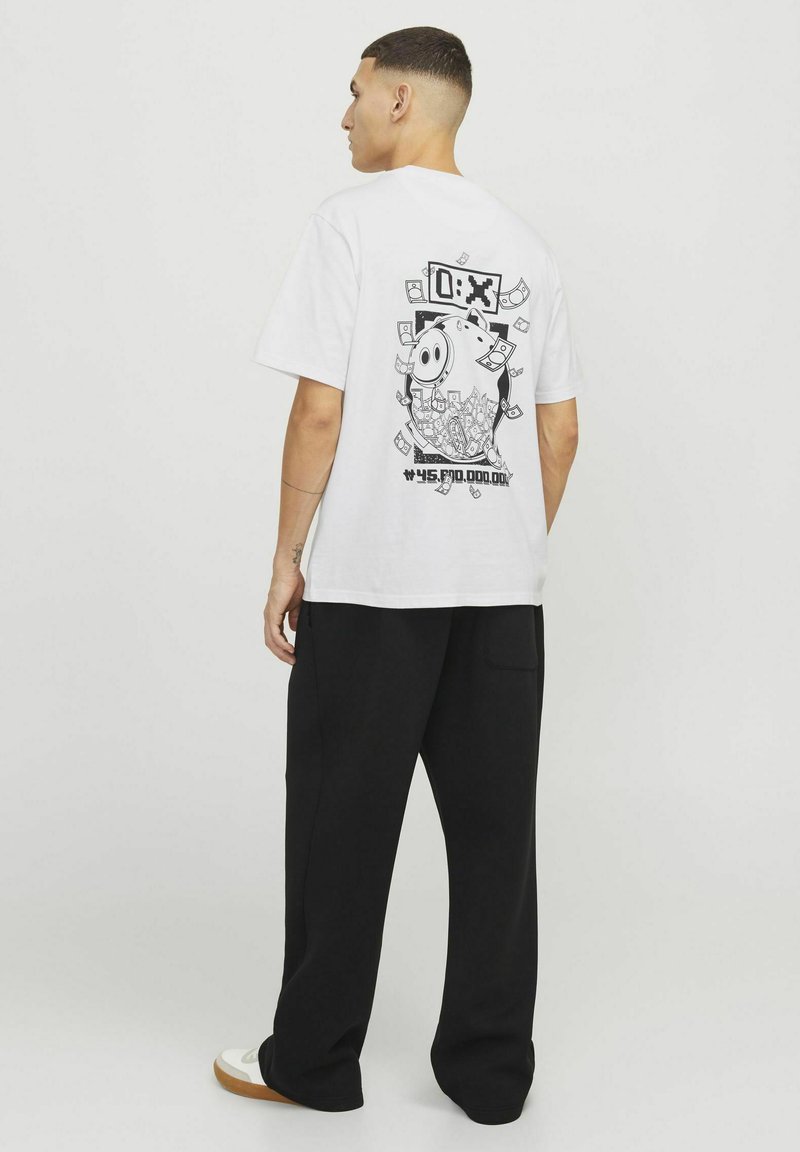 Hvid bomulds-t-shirt med et sort grafisk motiv af en sparegris omgivet af pengesedler på ryggen, parret med sorte løstsiddende bukser.