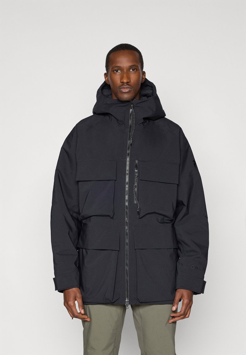 Black, insulated outerwear jacket with a zip front, large front pockets, and a hood. Made from smooth, weather-resistant material.