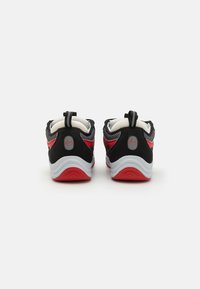 Zapatillas deportivas en negro y rojo con parte superior de malla texturizada, cuello acolchado, pestañas para tirar y una suela intermedia blanca con acentos rojos.