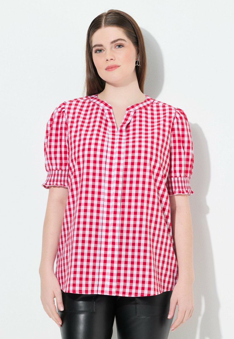 Chemise à carreaux rouge et blanc avec des manches courtes ballons, décolleté en V et poignets froncés. Matière douce avec une coupe ample, associée à un pantalon en simili cuir noir.