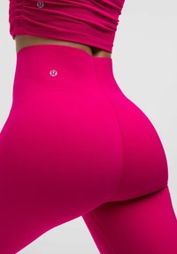 Korkeavyötäröiset, kirkkaanpunaiset legginsit, joissa on sileä pinta ja takasauman yksityiskohtia. Vyötärönauhassa on logo. Ompeleet näkyvät kauttaaltaan.