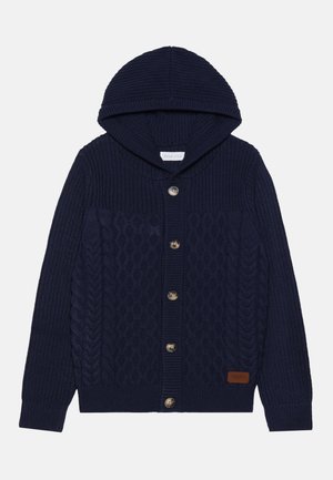 Cardigan lavorato a maglia di colore blu navy con cappuccio, caratterizzato da un design a treccia, grandi bottoni e una finitura testurizzata. Patch in pelle con logo sul lato inferiore.