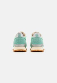 Baskets turquoise avec une tige lisse, des accents gris, un col rembourré et une semelle en gomme texturée. Comprend un logo et des trous de ventilation.