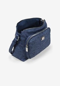 Bolso cruzado de mezclilla en azul oscuro con un patrón acolchado, dos compartimentos con cremallera y un acento en tono plata. Correa ajustable.