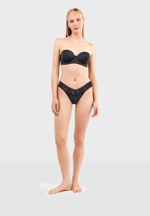 Sujetador negro sin tirantes con tela suave y copas moldeadas, combinado con bragas de bikini negras con encaje en los bordes en forma de V. Sin herrajes visibles.