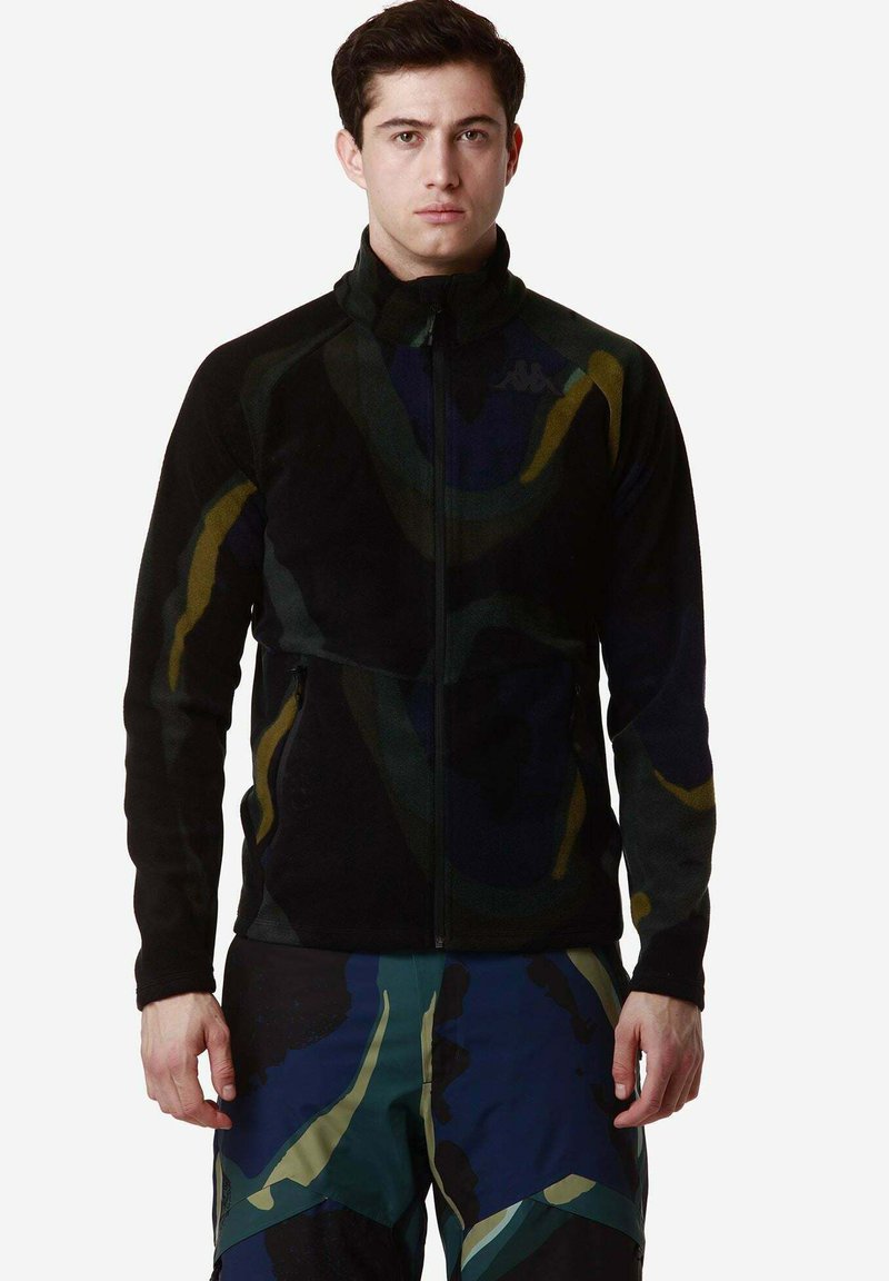 Giacca in pile con motivo astratto nero e multicolore, dotata di zip completa e colletto alto, realizzata in materiale morbido e testurizzato.