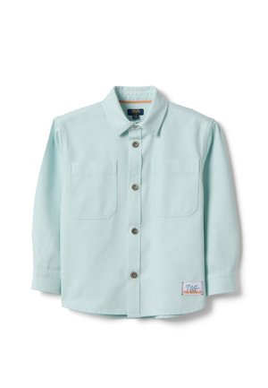 Lichtblauw overhemd met lange mouwen, knoopsluiting en twee borstzakken, met een klein "TAG THE WORLD"-patchje bij de zoom.