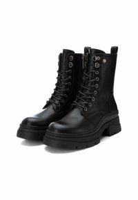 Botas de cuero negro con cordones, puntera redonda, suela de goma gruesa, cremallera lateral y ojetes de metal. Incluye bucles para facilitar el uso.