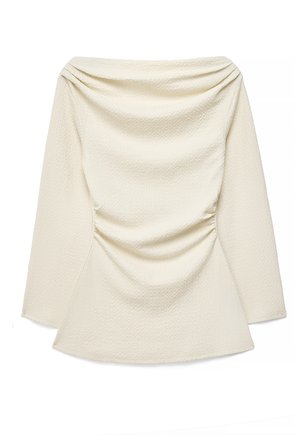 Białawy, teksturowany top z długim rękawem, szerokim dekoltem w łódkę i marszczonym detalem materiału w talii, ułożony na płaskiej powierzchni.