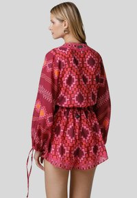 Capo d'abbigliamento con motivo floreale nelle tonalità di rosa e bordeaux; comodo, con maniche lunghe, vita elastica e dettagli con cordoncino.