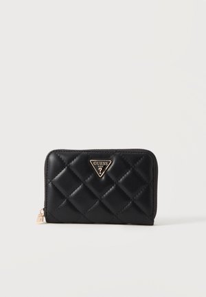 Portefeuille en cuir noir matelassé avec fermeture éclair dorée et logo Guess triangulaire doré sur le devant, sur fond blanc uni.