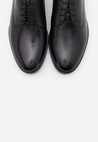Scarpe da dress in pelle nera con finitura liscia, punta affusolata e cinque paia di occhielli per i lacci. Design semplice senza decorazioni.