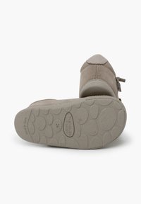 Scarpa in suede grigia con punta arrotondata. Parte superiore in morbido tessuto testurizzato, con un fiocco decorativo e una suola in gomma flessibile con trazione a motivo.
