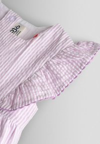 Top in tessuto a righe viola chiaro con maniche arricciate, bordi smerlati e un'etichetta sul collo. Tessuto morbido, design casual.