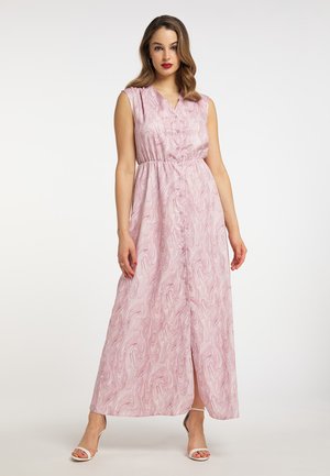 Vrouw draagt een mouwloze roze-witte gemarmerde maxi-jurk met knopen aan de voorkant, staand tegen een effen witte achtergrond.