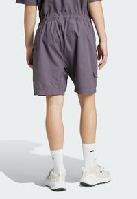 Lila shorts med elastisk midja, sidofickor och lätt tyg. Bärs med vita strumpor och ljusa sportskor.