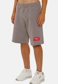 Gray cotton blend shorts with an elastic waistband, side pockets, and a red logo patch on the left thigh. Knee-length design.
