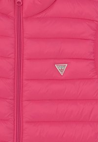 Gilet imbottito rosa con design a righe verticali, cerniera frontale completa e un piccolo badge triangolare sul lato sinistro. Texture liscia.